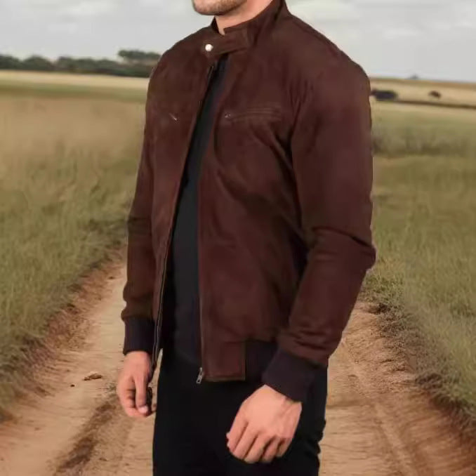 Man wearing a brown jacket standing on a dirt path in a field