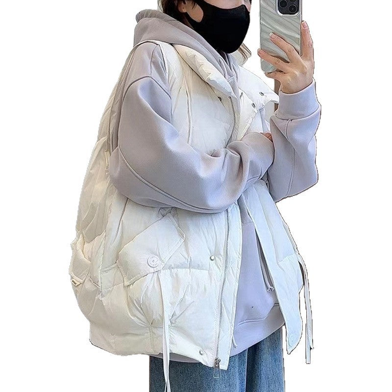 Person wearing a light gray puffer jacket over a white hoodie on a plain background