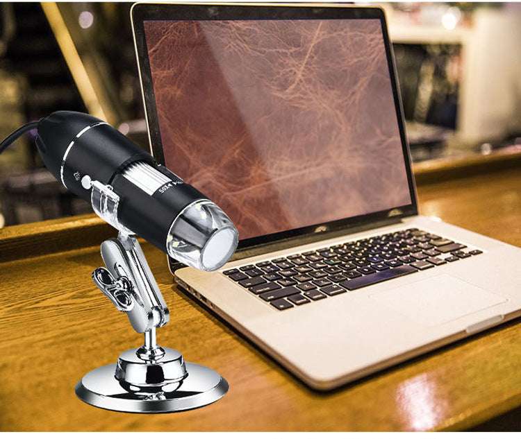 Digital microscope on a stand in front of a laptop displaying a leather texture.