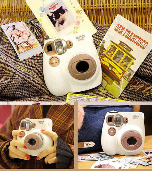 White instant camera with brown accents on a textured surface with travel-themed cards.