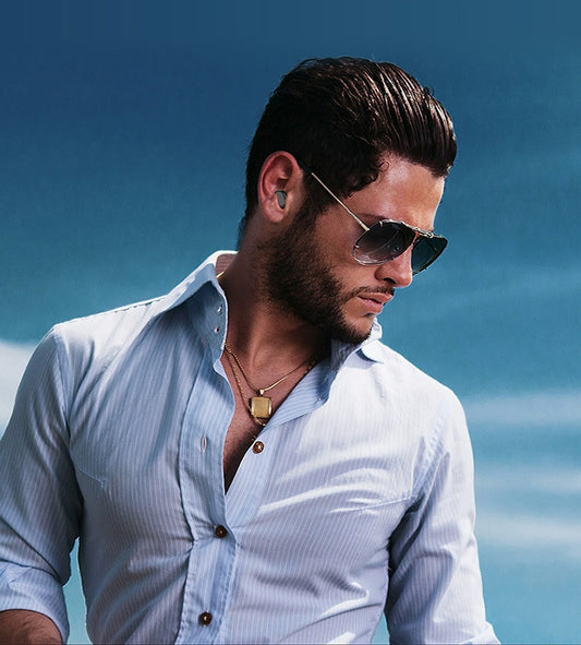 Man wearing sunglasses and a light blue shirt against a clear blue sky