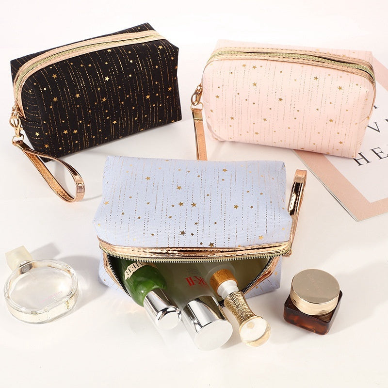 Three star cosmetic bags: black, light blue, and light pink with gold zippers