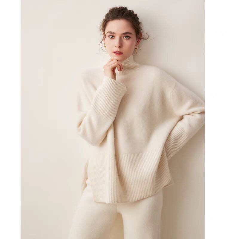 Woman wearing a cream-colored turtleneck sweater against a plain background