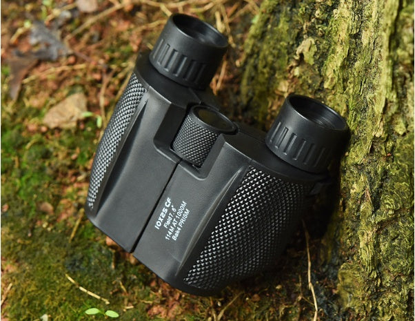 Black binoculars leaning against a tree in a natural setting