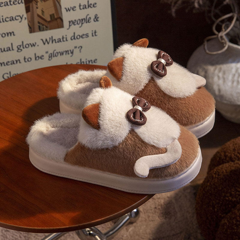 A pair of fluffy, cat-style slippers in beige and brown colors with a round toe design and flat heel, placed on a floor mat.