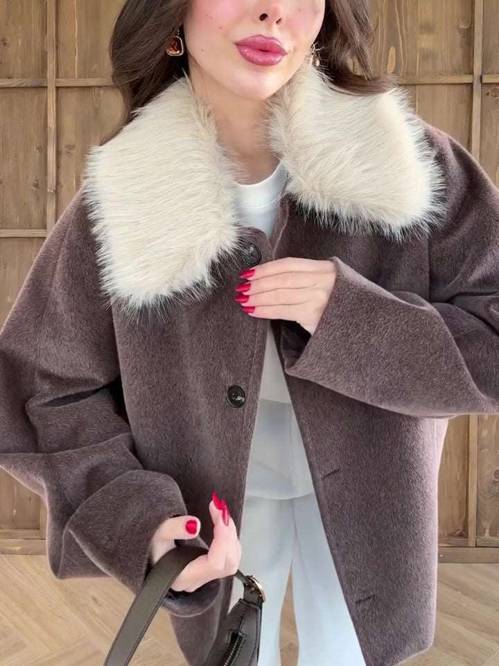 Woman wearing a brown coat with a fur collar against a wooden background
