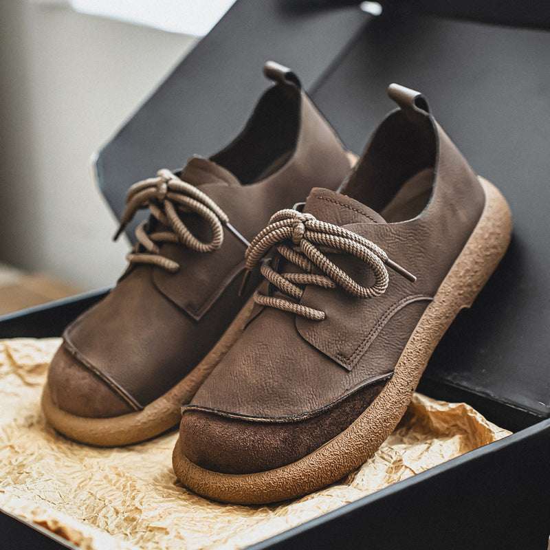 Pair of brown leather shoes with laces on a textured surface