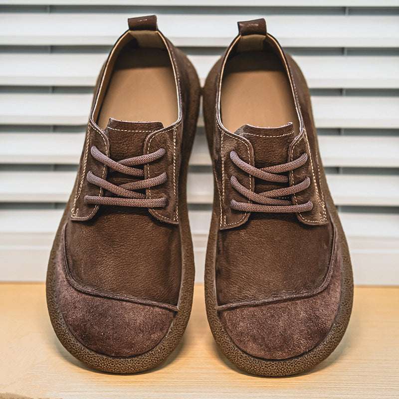 Pair of brown suede shoes on a wooden surface with a striped background