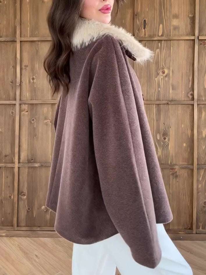 Brown cape with fur collar worn by a person against a wooden background