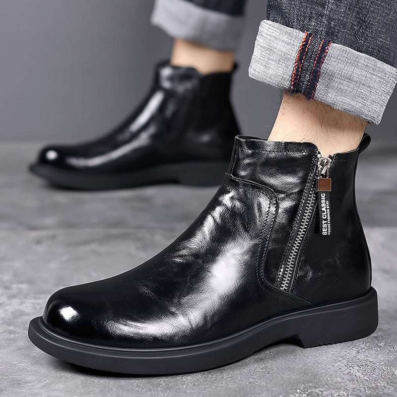 Black leather ankle boots with a zipper on a gray surface