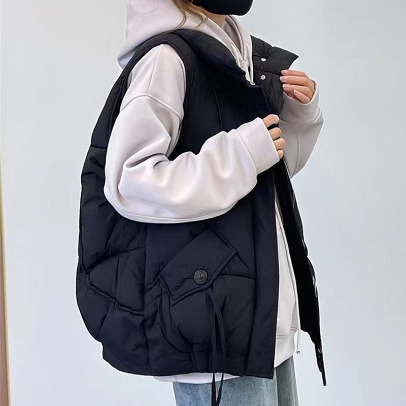 Person wearing a black puffer vest over a white hoodie on a light gray background