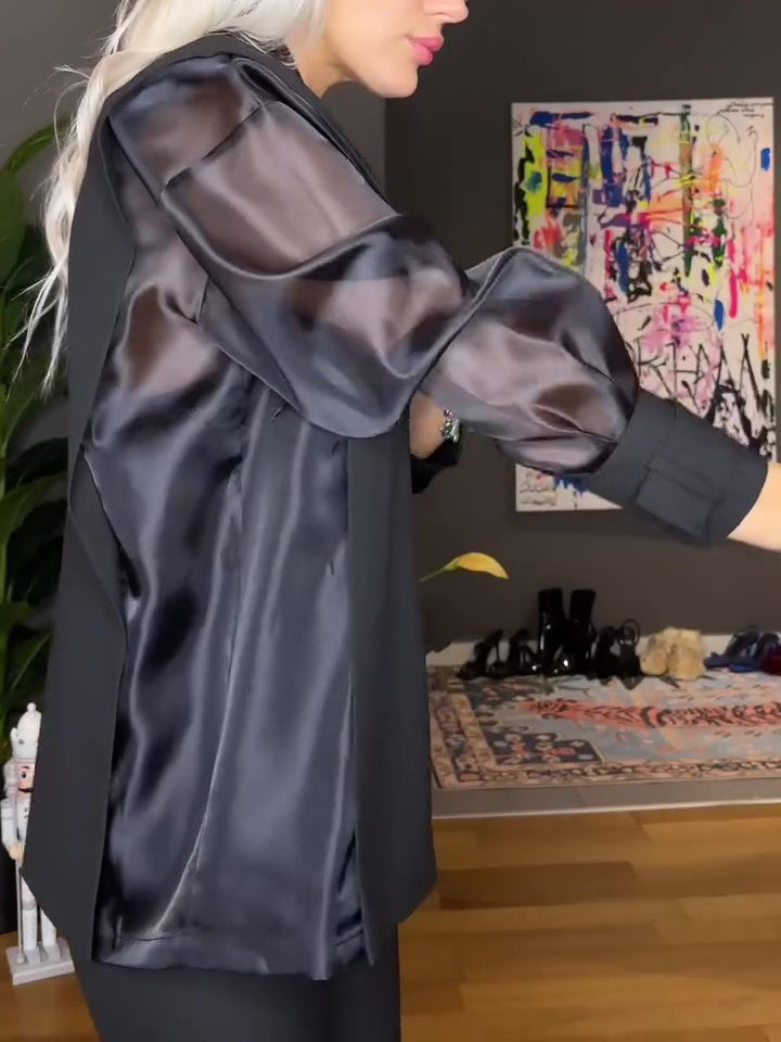 Person wearing a black satin dress in a room with colorful abstract art on the wall.