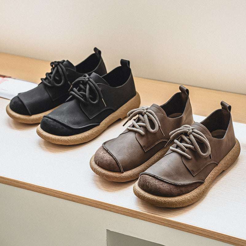 Pair of black and brown shoes on a wooden surface