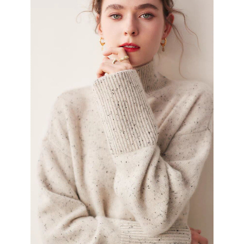Woman wearing a light gray turtleneck sweater with a plain background