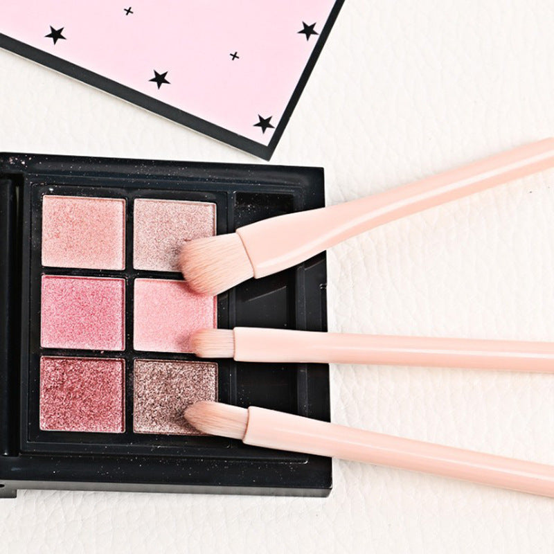 Makeup palette with pink and gold shades and brushes on a light background