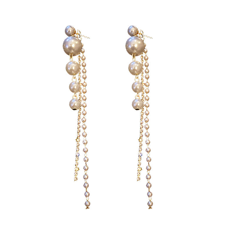 Pair of pearl earrings with gold chains on a white background
