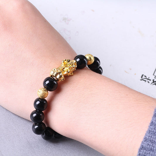 Gold bead bracelet with black round beads and ornate gold spacer charms