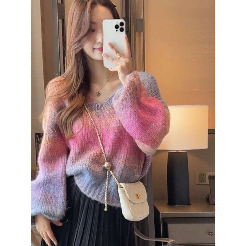 Woman wearing a colorful sweater taking a mirror selfie in a room.