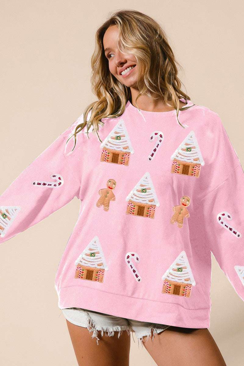 Woman wearing a pink sweater with gingerbread-themed designs on a beige background