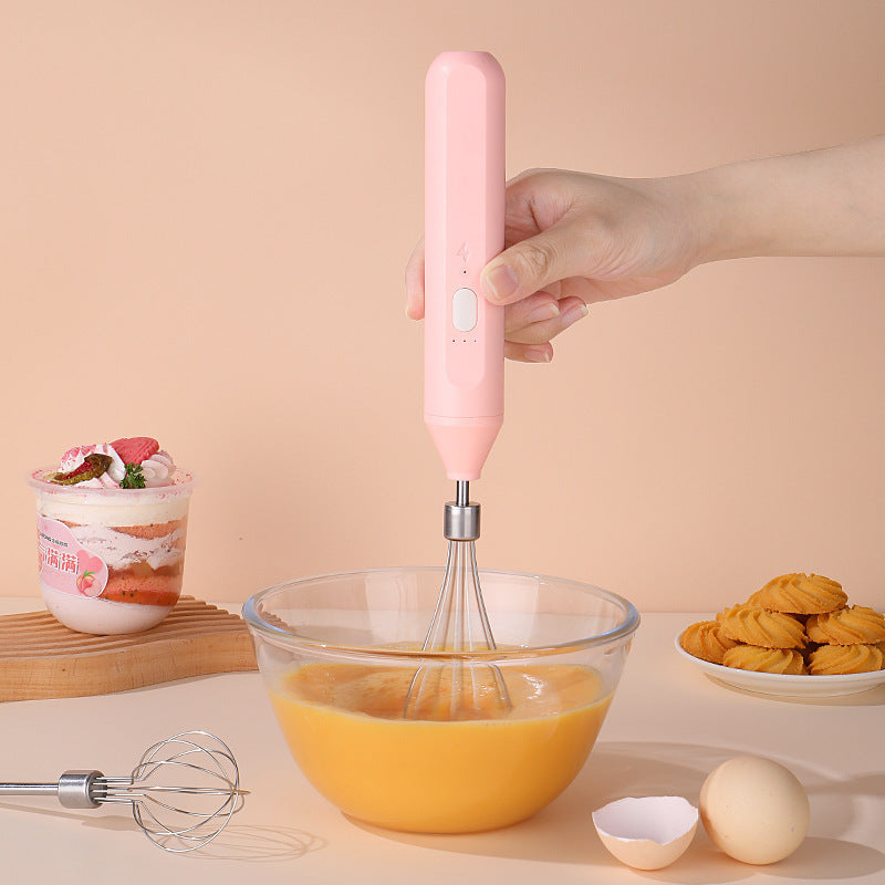 Hand holding a pink handheld whisk over a bowl of yellow liquid with a dessert and cookies in the background.