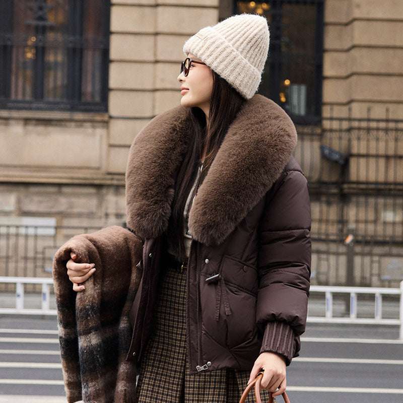 Woman wearing a brown fur-lined coat and white beanie in an urban setting