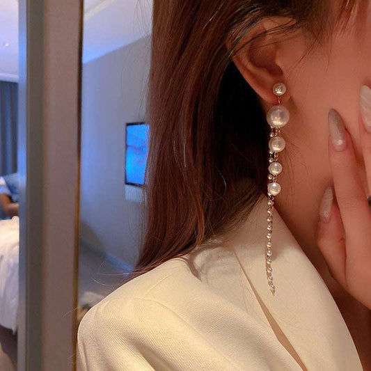 Close-up of a person wearing pearl earrings with a blurred background