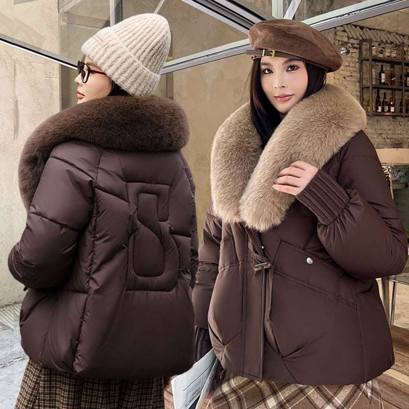 Woman wearing a brown winter coat with fur collar in front of a mirror.