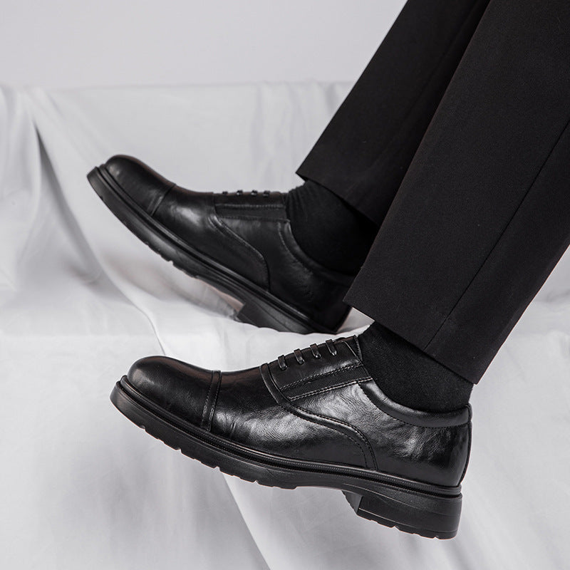 Black leather dress shoes worn with black pants on a light gray background