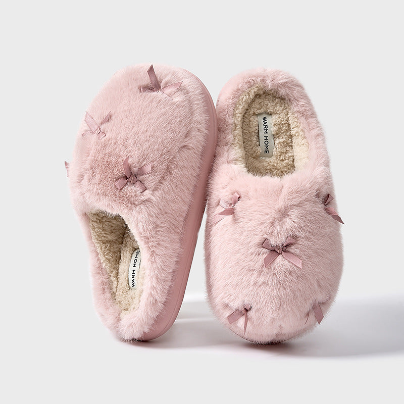 A set of women's plush home slippers with butterfly knot design. The slippers are shown in beige, white, and pink colors with a round toe and thick sole.