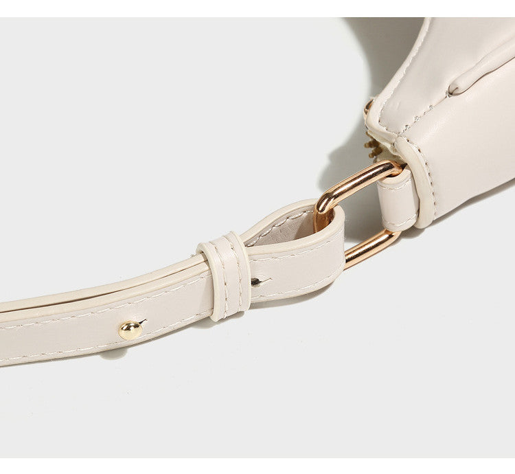 Cream crossbody bag close-up with gold-tone clasp and stitched strap detail