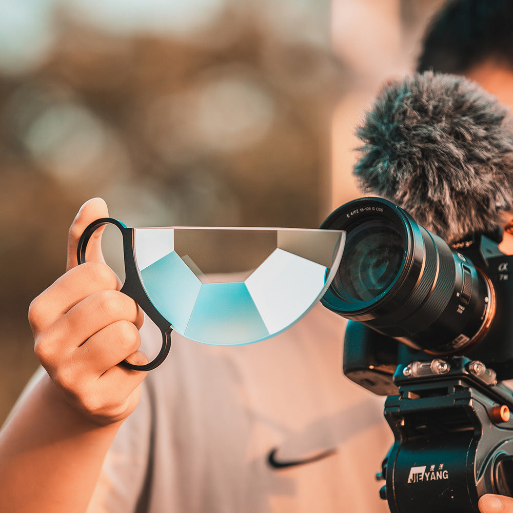 Camera with lens cap held by a hand, blurred natural background