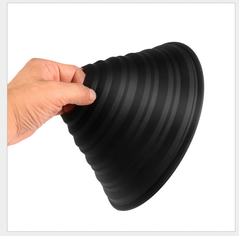 Black collapsible dog bowl held by a hand on a white background
