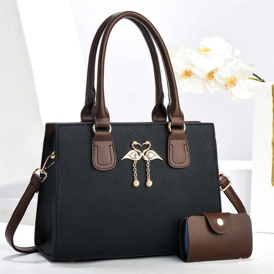 Black large crossbody tote bag with brown handles, front heart charm, and side pouch