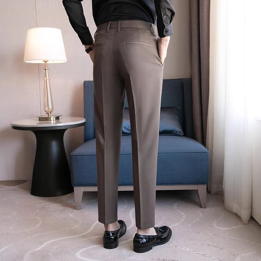 A man modeling dapper British-style dress pants with a crisp crease and tailored fit, paired with leather brogues and a tucked-in dress shirt.