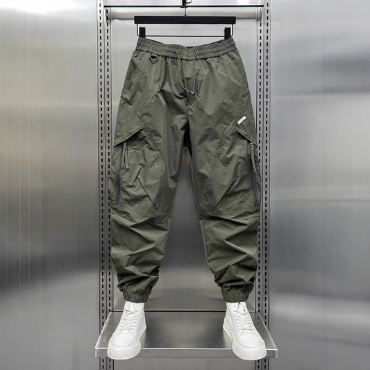 A man modeling lightweight tapered cropped pants that sit just above the ankle, styled with clean white sneakers for a trendy summer streetwear look.