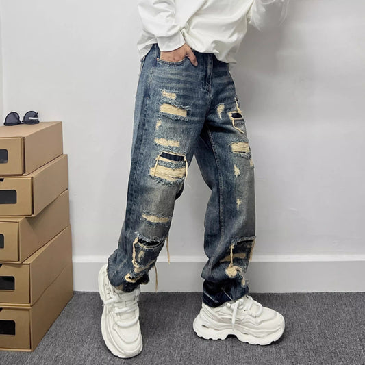 A man modeling slim-fit American casual jeans featuring stylish ripped knees, textured fabric patches, and an authentic vintage wash.