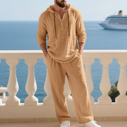 A man relaxing at home wearing a coordinated two-piece lounge set consisting of a long-sleeve hooded pullover and matching relaxed-fit joggers.