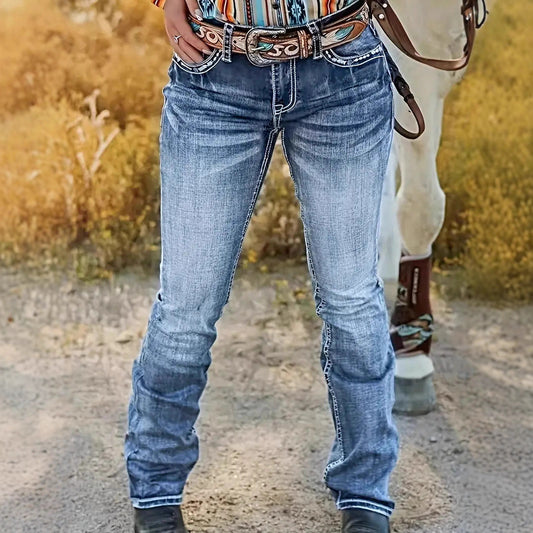 A woman modeling high-waisted straight-leg denim jeans featuring intricate Hatchet Man embroidery and a vintage heavy-industry washed texture.