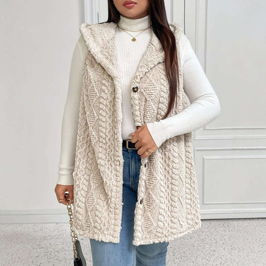 Person wearing a beige knitted vest over a white sweater with a neutral background