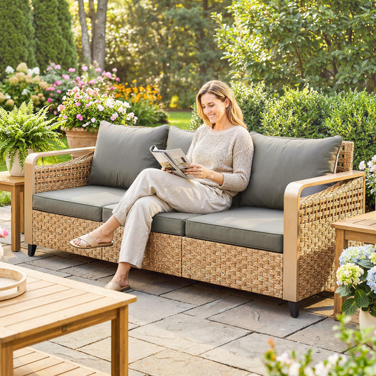 Gray 3-seater rattan wicker outdoor sofa with plush cushions on a modern backyard patio
