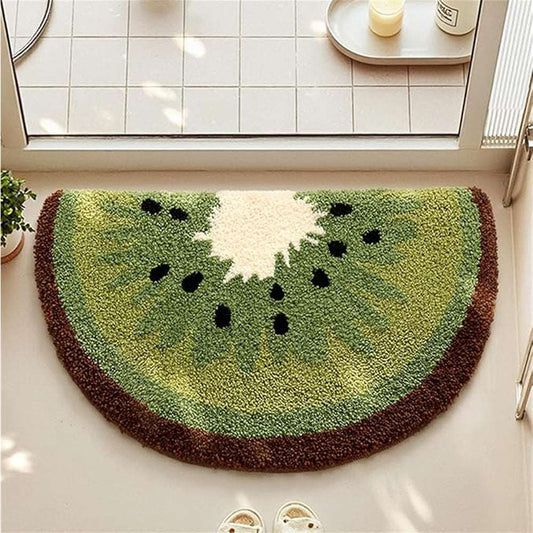 Green kiwi-shaped plush bath mat with black seed details on a clean bathroom floor
