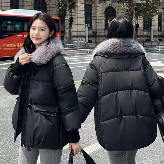 Woman wearing a black puffer jacket with a fur-lined hood on a city street.