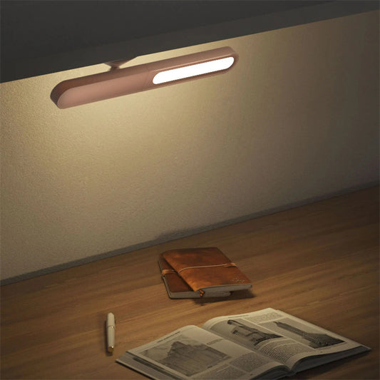 Wall-mounted light fixture illuminating a wooden floor with a book and pen.