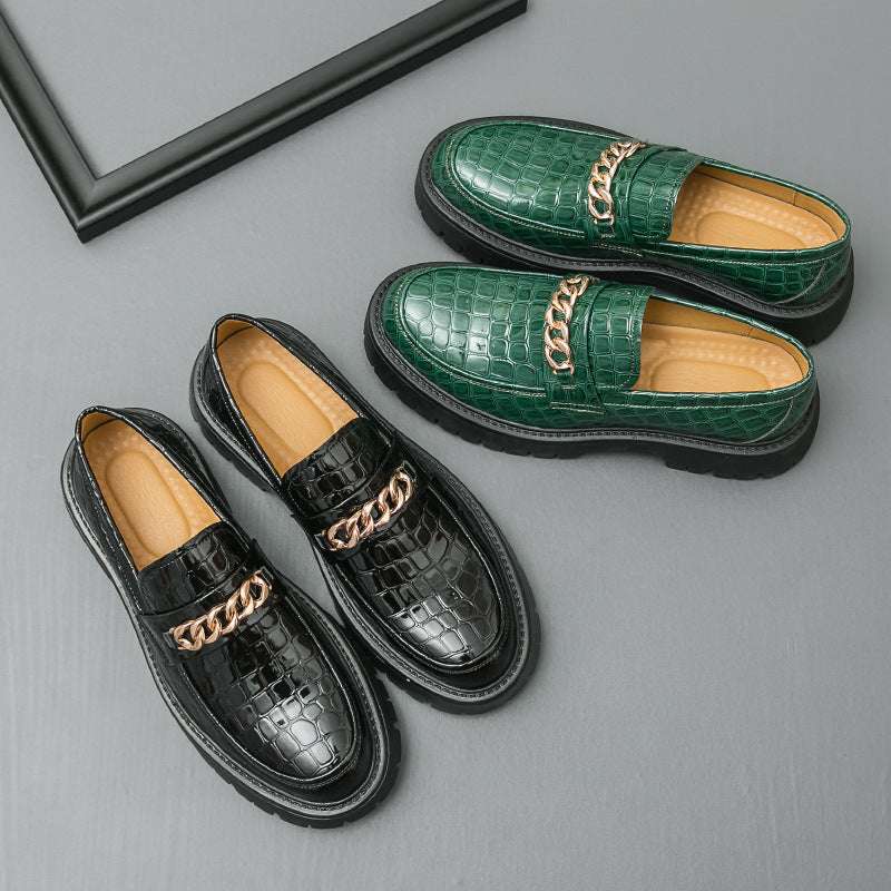 Green and black loafers with gold chain details on a gray surface