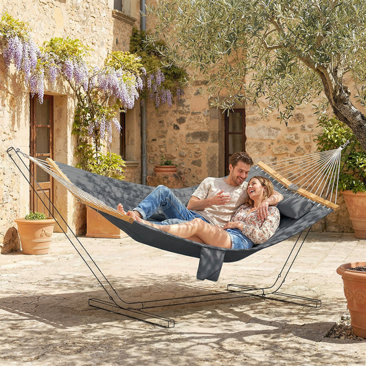 Modern gray 2-person outdoor hammock with a matching pillow and comfortable padded liner hanging in a contemporary backyard