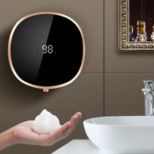 Digital soap dispenser on a bathroom wall with a hand holding soap next to it.