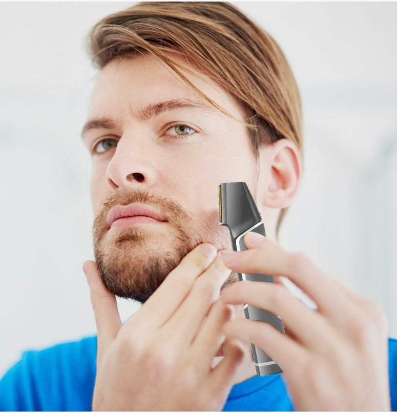 Man using an electric razor on his beard with a plain background
