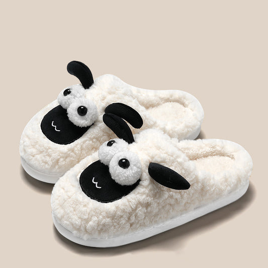 A pair of white slip-on slippers with a sheep design, featuring black and gray details on a plush upper.