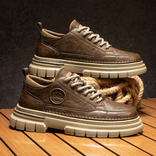 Brown leather sneakers with white soles on a wooden surface