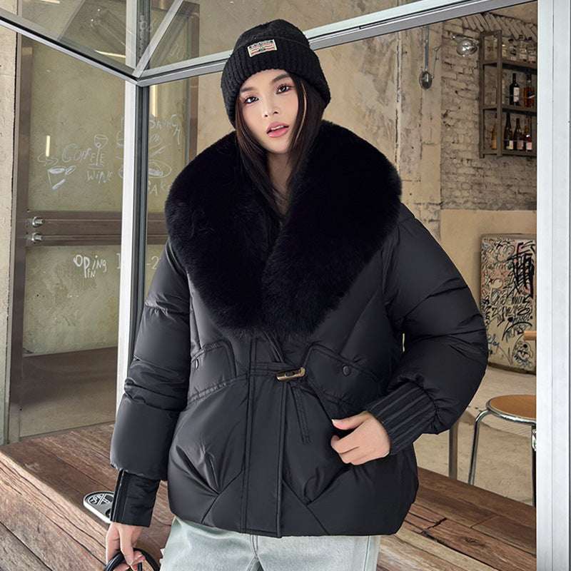 Person wearing a black coat with a fur collar in an urban setting